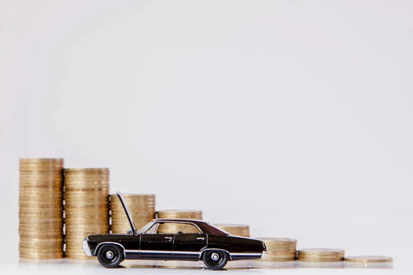 Un modello nero di un'auto con monete sotto forma di istogramma su sfondo bianco. Concetto di prestito, risparmio, assicurazione . — Foto Stock
