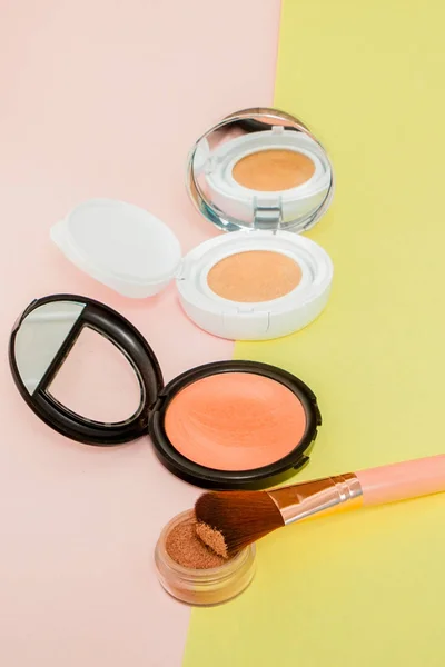 Maquillaje de productos que se derrama en un fondo amarillo brillante y rosa — Foto de Stock