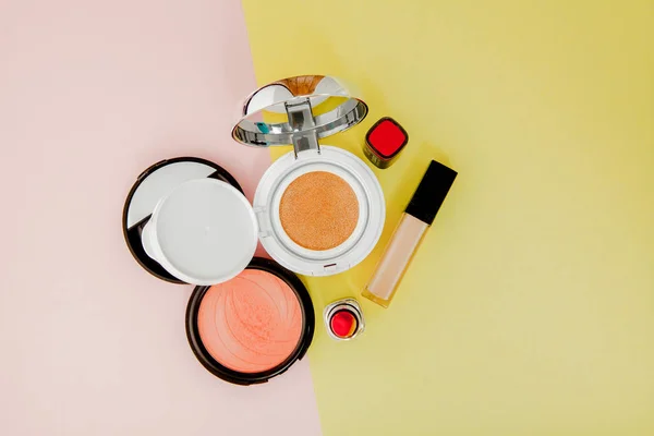 Trucchi i prodotti che versano sopra ad un backgro giallo e rosa luminoso — Foto Stock