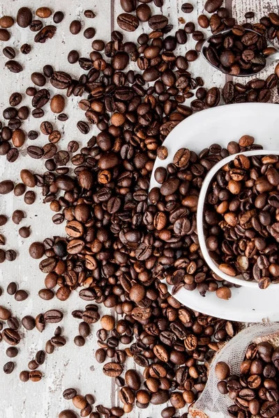 Černou kávu v bílém šálku a kávovou fazoli na světle dřevěném pozadí. Pohled shora, prostor pro text — Stock fotografie