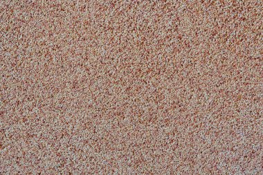 Yayılmış kum taneciklerinin arka planında bir taş kırıntısı var. Bir duvarın yüzeyinin dokusu, açık renk