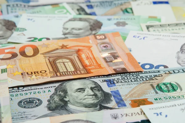 Geld en Financiën concept. Honderd nieuwe dollarbiljet op kleurrijke abstracte achtergrond van Oekraïens, Amerikaanse en nationale valuta eurobankbiljetten — Stockfoto