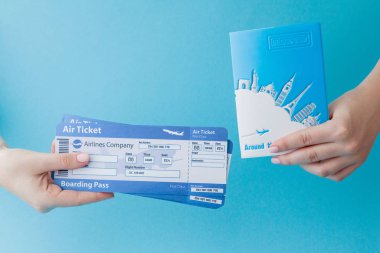 Mavi arka planda kadın el pasaport ve uçak bileti. Trav
