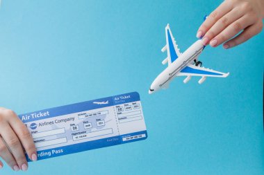 Mavi arka planda kadın el uçak ve hava bileti. Seyahat 