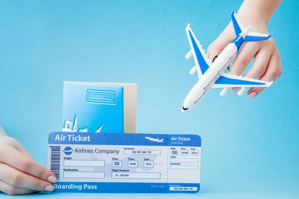 Passport, plane and air ticket in woman hand on a blue backgroun