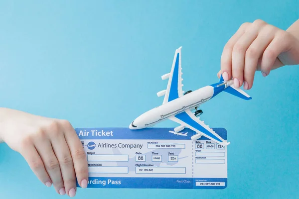 Plane and air ticket in woman hand on a blue background. Travel