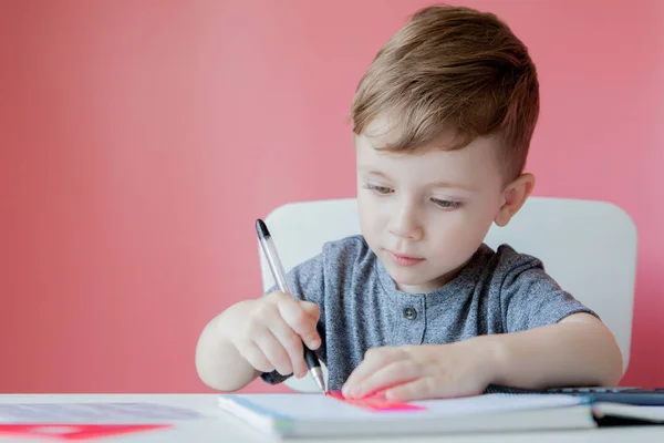 Портрет симпатичного хлопчика вдома, який робить домашнє завдання. Маленький концентрат — стокове фото