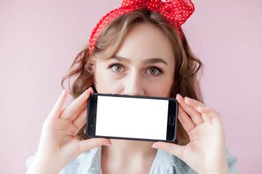 Pin-up makyaj ve saç modeli ile hareket eden telefon kopya alanı ile pembe arka plan üzerinde olan güzel kadın