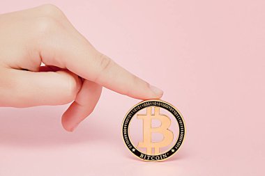 Parlayan yeni altın bitcoin pembe bir arka plan, metin için kopya yer tutan el kadındır