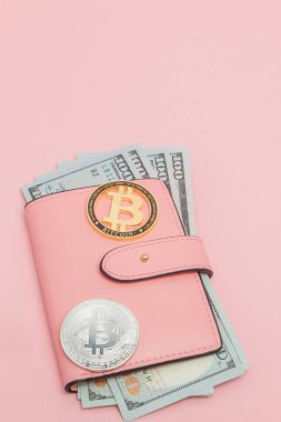 Pembe arka planda fotokopi alanı olan pembe bir cüzdanda Bitcoin ve dolar