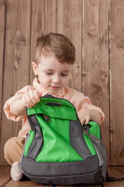 Niño pequeño con bolsa de escuela grande sobre fondo de madera — Foto de Stock