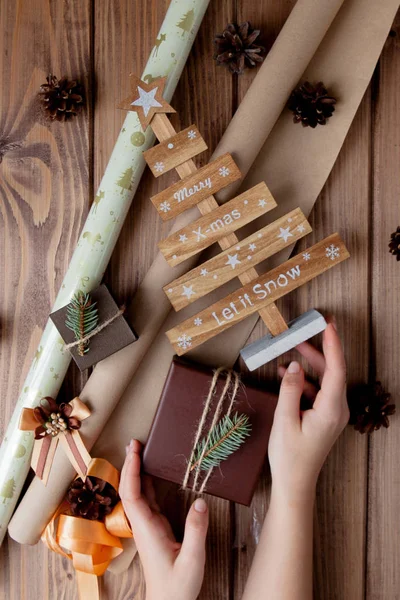 Cadeaux de Noël enveloppés dans du papier artisanal sur une table en bois. Processus d'emballage des cadeaux. Mode de vie. Vue d'en haut. Concept de Noël — Photo