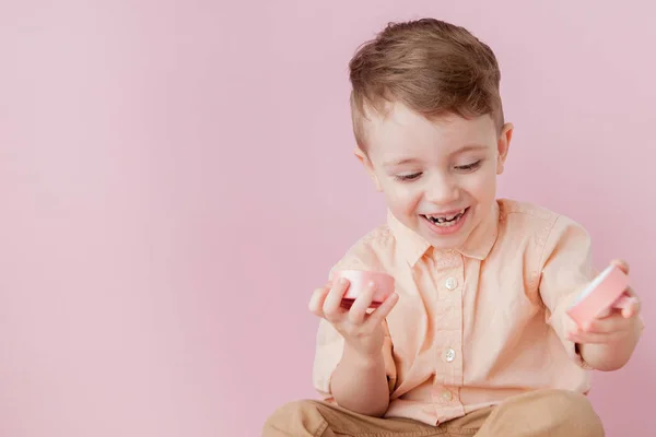 Un niño feliz con un regalo. Foto aislada sobre fondo rosa. El chico sonriente sostiene la caja presente. Concepto de vacaciones y cumpleaños — Foto de Stock