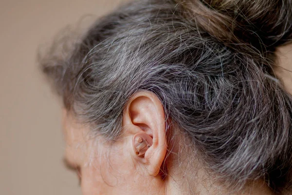 特写高级女人在她的耳朵中插入助听器 — 图库照片
