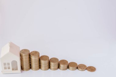 Beyaz bir arka plan üzerinde bir histogram şeklinde sikke ile bir araba ve ev siyah bir model. Kredi kavramı, tasarruf, sigorta.