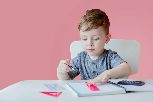 Portret van schattige jongen thuis maken huiswerk. Weinig geconcentreerd kind schrijven met kleurrijke potlood, binnenshuis. Basisschool en onderwijs. Kid Learning schrijven letters en cijfers — Stockfoto