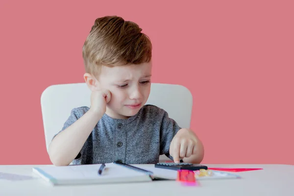 宿題を作る家でかわいい子供の男の子の肖像画。カラフルな鉛筆で書く小さな集中した子供、屋内。小学校と教育。文字と数字を書くことを学ぶ子供 — ストック写真