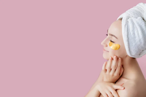 Retrato de la mujer de belleza con parches para los ojos sobre fondo rosa. Mujer cara de belleza con máscara bajo los ojos. Hermosa hembra con maquillaje natural y parches de colágeno de cosméticos dorados en la piel facial fresca — Foto de Stock