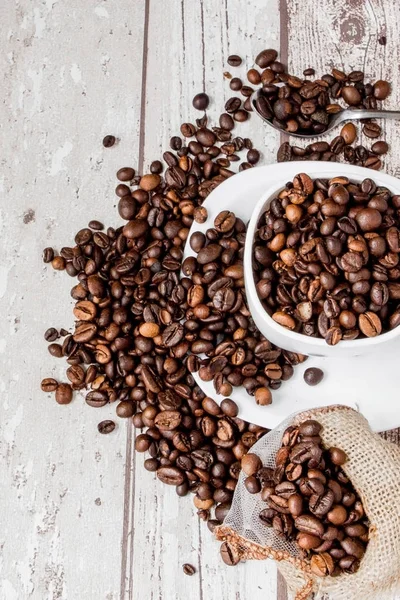 stock image Black coffee in white cup and coffee beans on light wooden backg