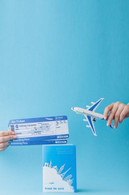 Pasaport, uçak ve hava bileti kadın elinde mavi bir arka planda. Seyahat konsepti, kopya alanı