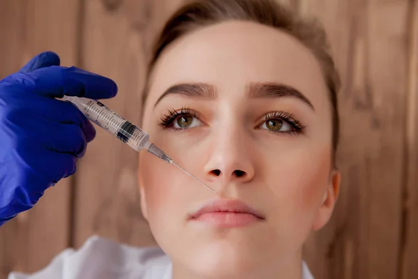 Dokter in handschoenen geven vrouw botox injecties in de lippen, op roze — Stockfoto