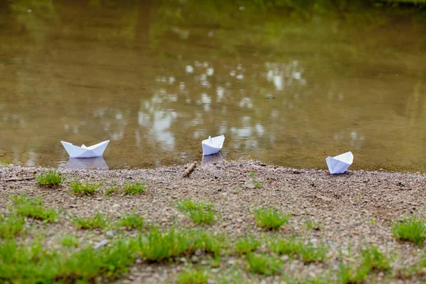 Bateau jouet en papier blanc sur l'eau bleue près du rivage — Photo