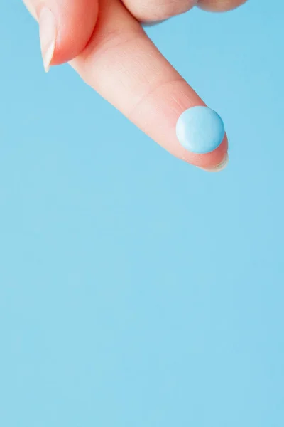 Foto de close-up de pílula azul na mão da enfermeira isolada sobre fundo azul. Espaço de cópia — Fotografia de Stock