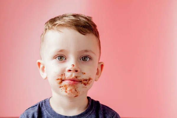 Niño comiendo chocolate. Lindo niño feliz untado con chocolate alrededor de su boca. Concepto infantil . — Foto de Stock