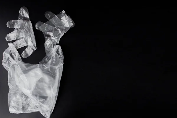 Bolsa de plástico con asas, guantes, sobre fondo negro. Usado p — Foto de Stock