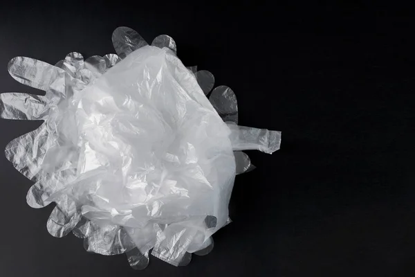 Sac en plastique avec poignées, gants, sur fond noir. Sac en plastique utilisé pour le recyclage. Concept - écologie, pollution de la planète par le polyéthylène cellophane plastique — Photo