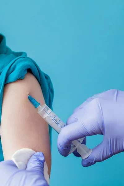 Vaccinatie concept. Vrouwelijke arts vaccineren schattige kleine jongen op blauwe achtergrond, close-up — Stockfoto