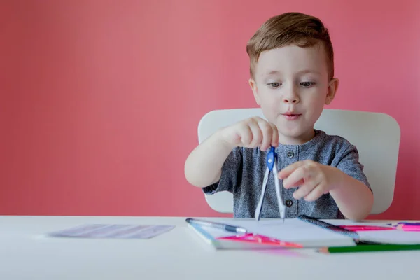 Portret van schattige jongen thuis maken huiswerk. Weinig geconcentreerd kind schrijven met kleurrijke potlood, binnenshuis. Basisschool en onderwijs. Kid Learning schrijven letters en cijfers — Stockfoto