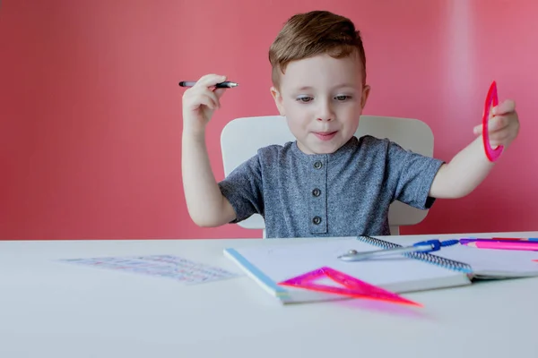 Portret cute chłopiec Kid w domu podejmowania pracy domowej. Mało skoncentrowane dziecko piśmie z kolorowym ołówkiem, w pomieszczeniu. Szkoła podstawowa i edukacja. Kid nauka pisania listów i liczb — Zdjęcie stockowe