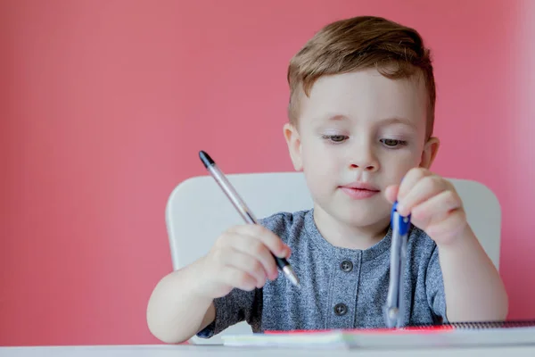 Portret cute chłopiec Kid w domu podejmowania pracy domowej. Mało skoncentrowane dziecko piśmie z kolorowym ołówkiem, w pomieszczeniu. Szkoła podstawowa i edukacja. Kid nauka pisania listów i liczb — Zdjęcie stockowe