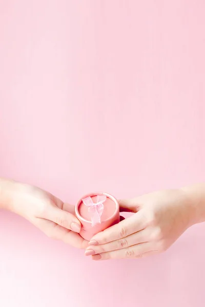 Scatola regalo rotonda rosa nelle mani delle donne su uno sfondo rosa. Concetto festivo per San Valentino, festa della mamma o compleanno — Foto Stock