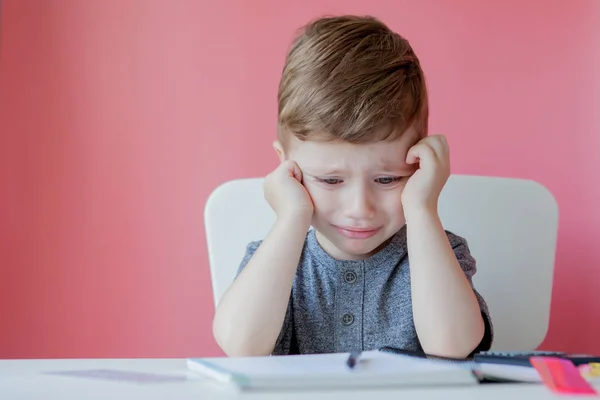 宿題を作る家でかわいい子供の男の子の肖像画。カラフルな鉛筆で書く小さな集中した子供、屋内。小学校と教育。文字と数字を書くことを学ぶ子供 — ストック写真