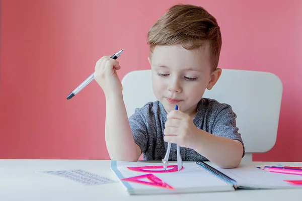 Portré aranyos gyerek fiú otthon így házi feladatot. Little koncentrált gyermek írás színes ceruzával, beltéri. Általános iskola és oktatás. Gyerek tanulás írásban betűk és számok — Stock Fotó