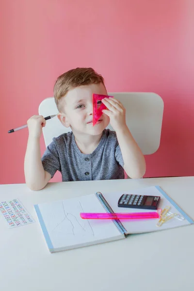 Retrato de menino bonito em casa fazendo lição de casa. Pequena criança concentrada escrevendo com lápis colorido, dentro de casa. Escola primária e educação. Criança aprendendo a escrever letras e números — Fotografia de Stock