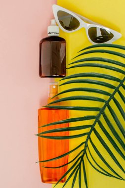 Parlak kare sarı ve pembe arka planda şişe güneş kremi. Denizde tatil konsepti, yaz zamanı. Üst görünüm, düz yatıyordu, Minimalizm, kopya alanı