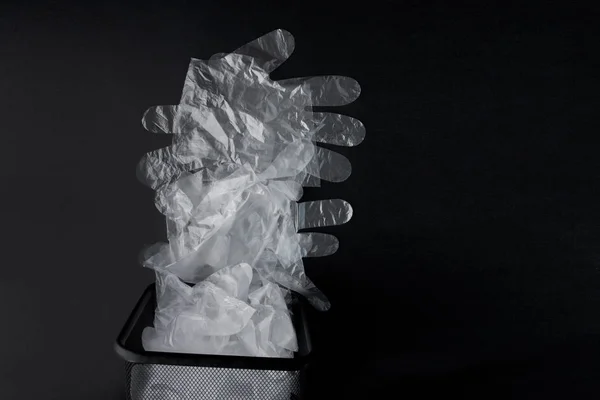 Bolsa de plástico con asas, guantes en la papelera sobre un fondo negro — Foto de Stock