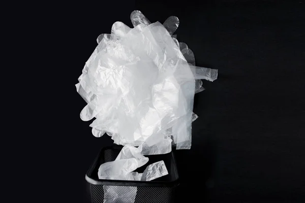 Sacchetto di plastica con manici, guanti nel cestino su un backgroun nero — Foto Stock