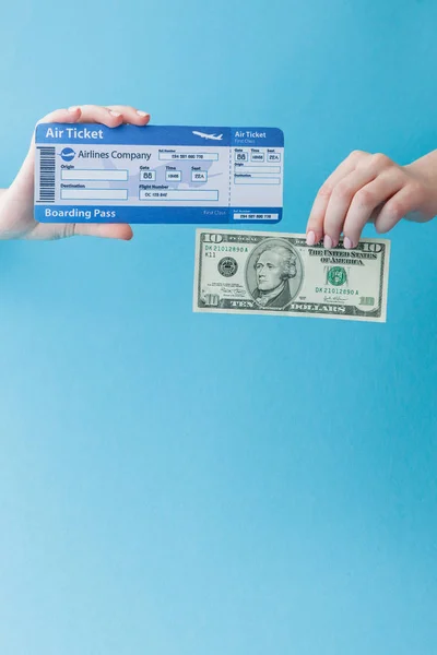 Dólares e passagem aérea na mão de mulher em um fundo azul. Trave. — Fotografia de Stock