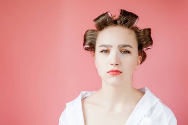 Yüzüne dokunmadan bir maske ve curlers ile güzel genç kız.