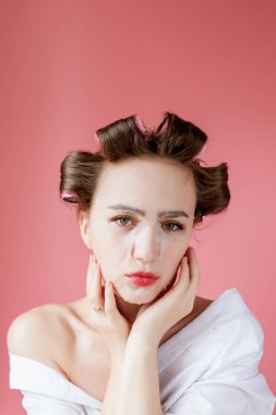 Yüzüne dokunmadan bir maske ve curlers ile güzel genç kız.