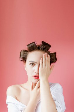 Yüzüne dokunmadan bir maske ve curlers ile güzel genç kız.