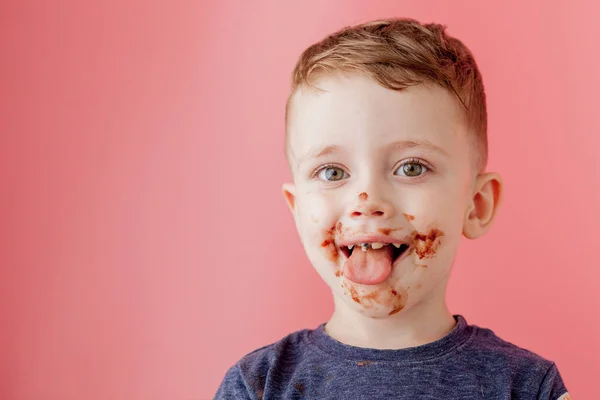 Rapaz a comer chocolate. Bonito menino feliz manchado com chocola — Fotografia de Stock