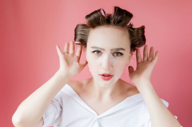 Yüzüne dokunmadan bir maske ve curlers ile güzel genç kız.
