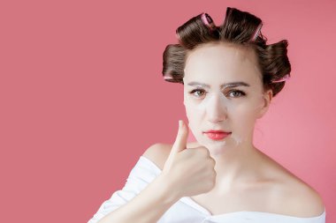 Yüzüne dokunmadan bir maske ve curlers ile güzel genç kız.