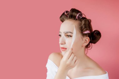 Yüzüne dokunmadan bir maske ve curlers ile güzel genç kız.