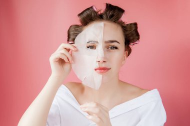 Yüzüne dokunmadan bir maske ve curlers ile güzel genç kız.